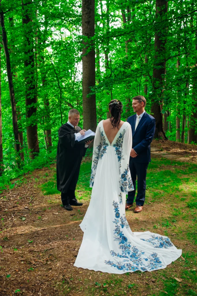 Ellie and Doug standing with their officiant during their woodland wedding ceremony at Vixen Hill Farm