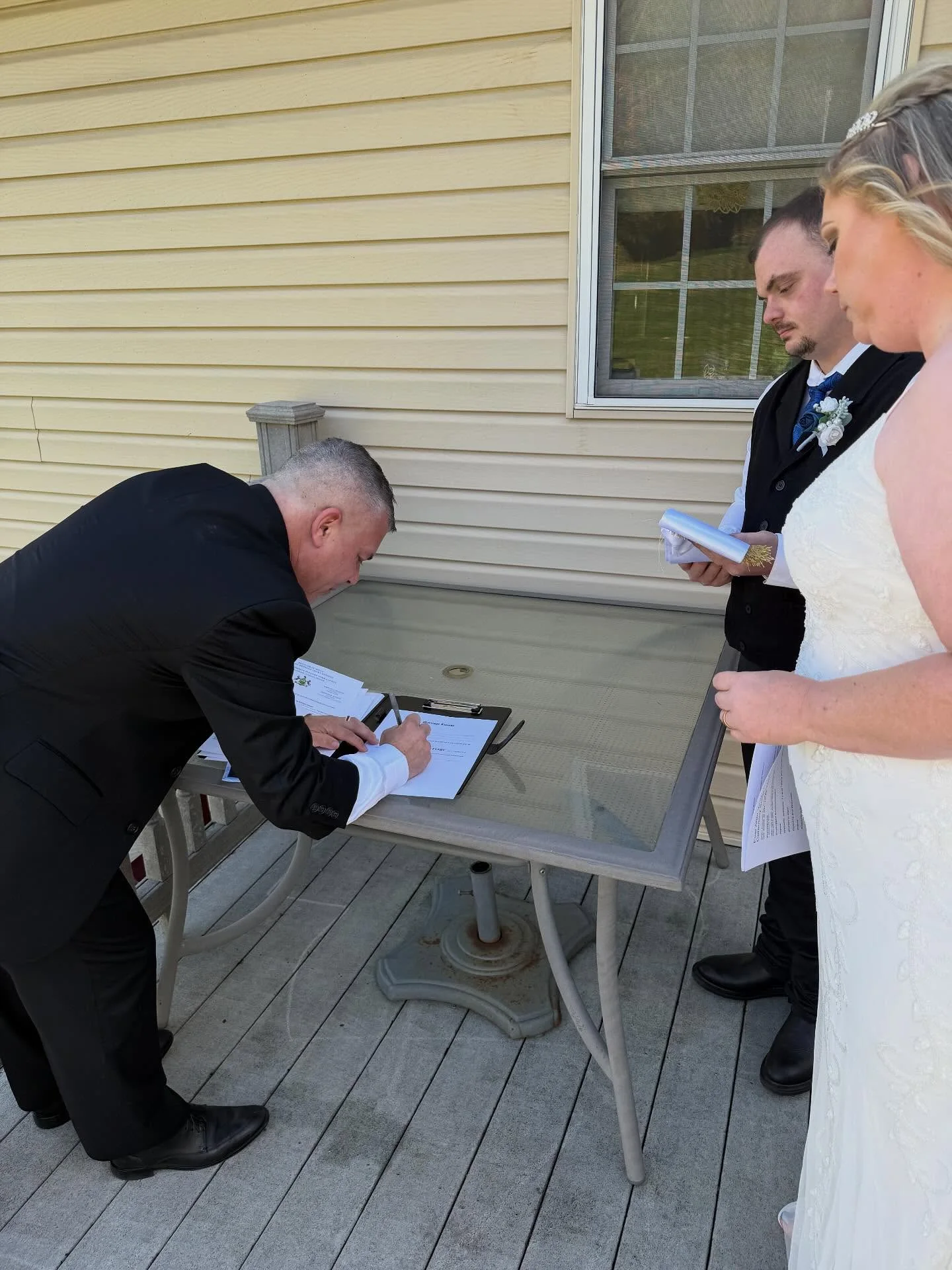 Marriage license signing at a couple’s home—officiant completing paperwork on the deck table.