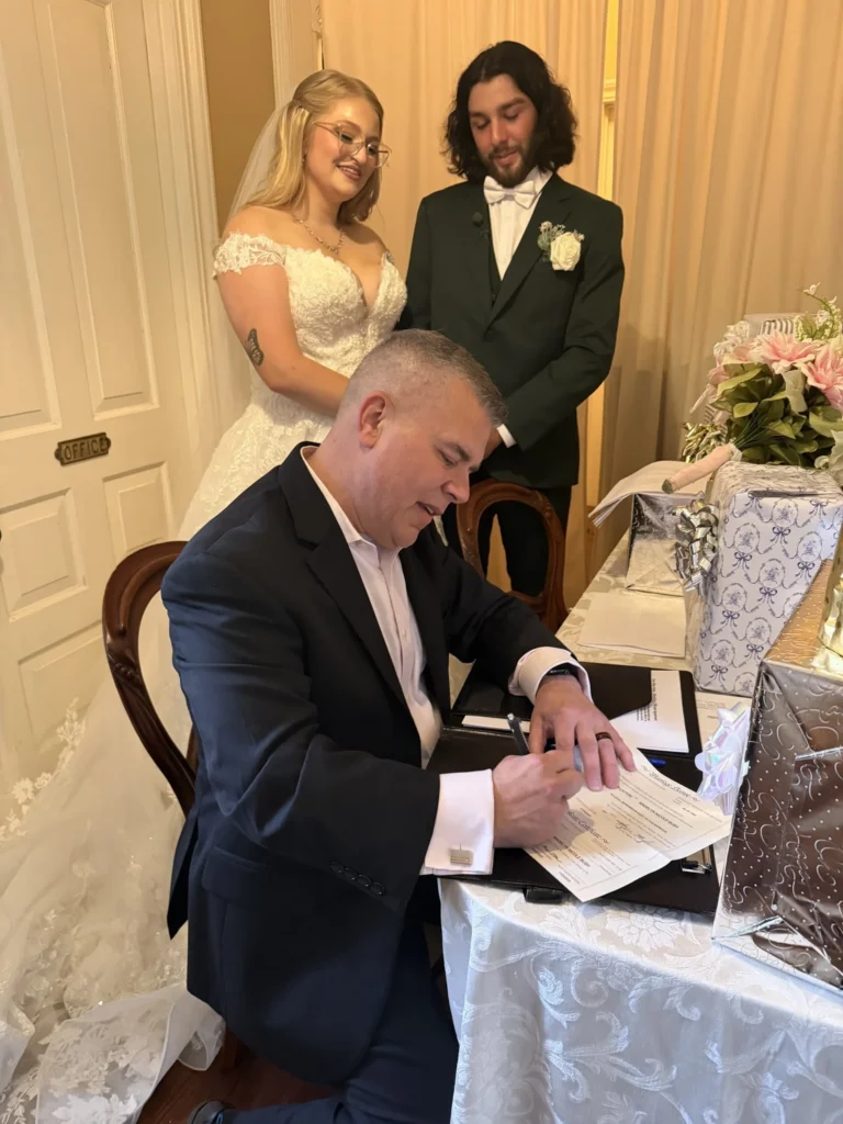 Couple signing their marriage license with the officiant guiding the process