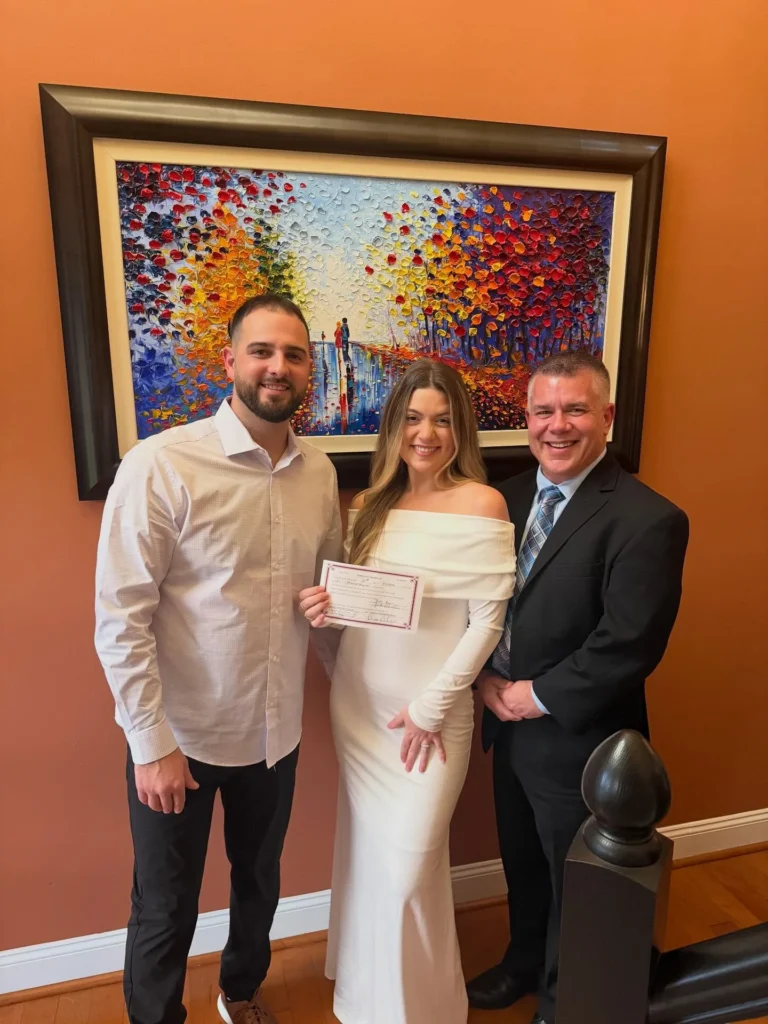 Ever After Vows officiant with newlywed couple holding their marriage license after an intimate indoor ceremony
