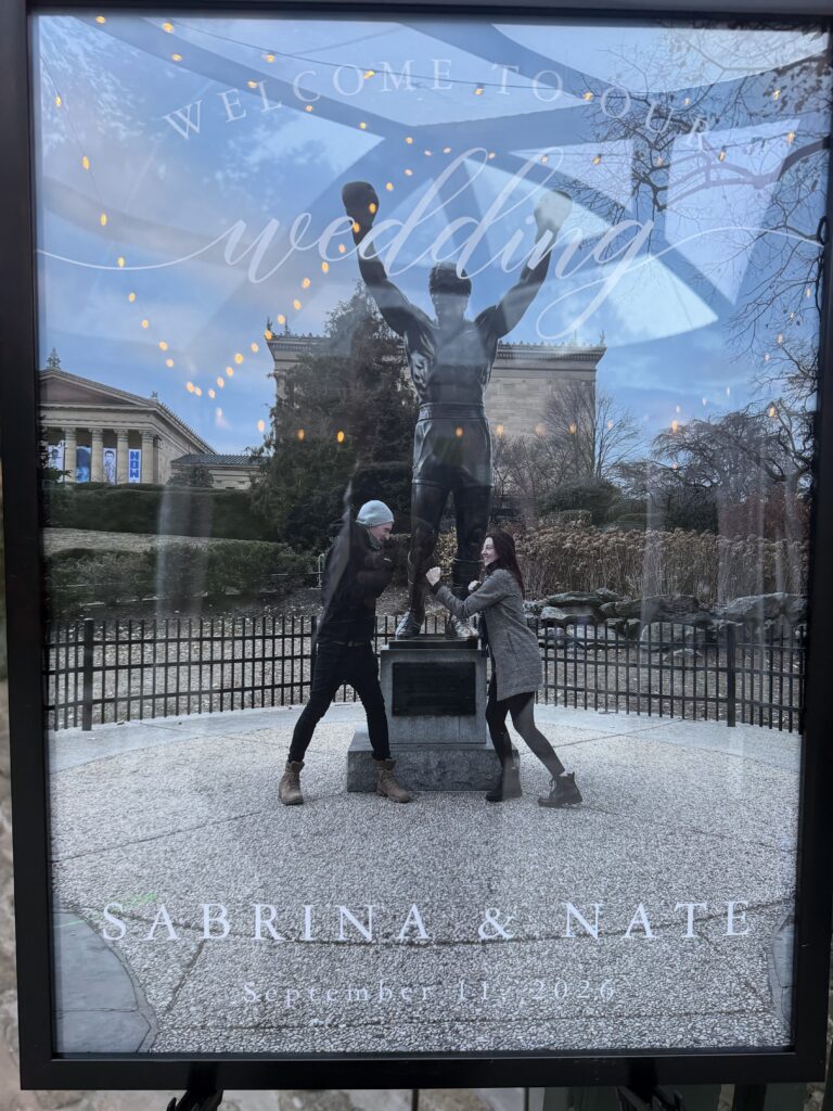 A framed wedding welcome display for Sabrina and Nate features the Rocky statue in Philadelphia and their September 11, 2026 wedding date.